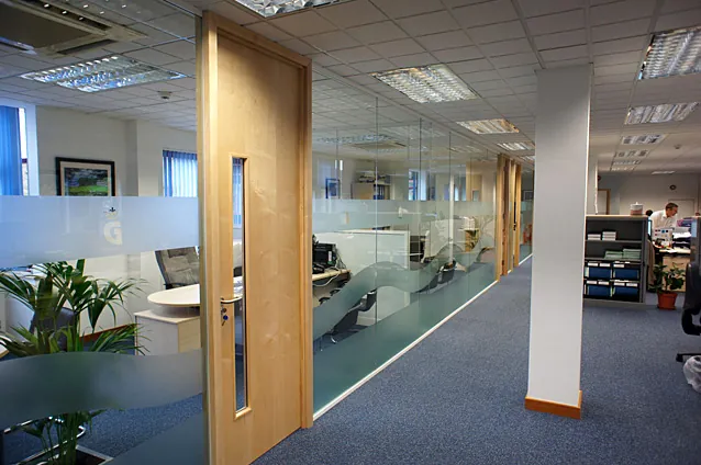 Glazed partitioning with a timber door and frosted manifestation